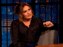 a woman in a black shirt is sitting in a chair with her hands outstretched