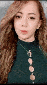 a close up of a woman wearing a green sweater and a necklace with circles on it