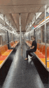 a man is sitting on a subway car with empty seats