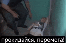 a man is laying on the floor with his arms outstretched while a police officer looks on .
