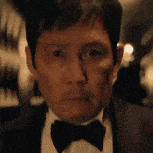 a close up of a man in a suit and bow tie .