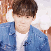 a young man wearing a blue denim jacket and white shirt