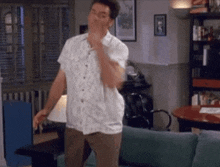 a man is standing in a living room with his hand on his chin