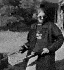 a black and white photo of a man holding a sword in front of a building .