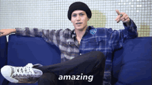 a man is sitting on a blue couch and the word amazing is on the bottom right