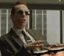a man in a suit and tie is holding two bongos in his hands
