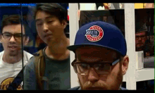 a man wearing a supply company hat stands in front of two other men