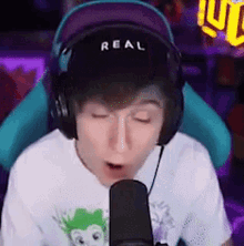 a boy wearing headphones and a hat is talking into a microphone .
