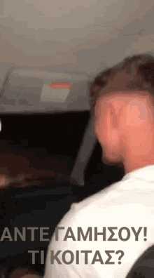 a man sitting in a car with the words ante gamhsoy ti koitas written on the bottom