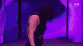 a woman in a black tank top is standing in front of a purple wall .