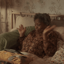 an elderly woman in a floral shirt is laying on a bed