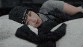 a woman laying on a bed wearing a black hat