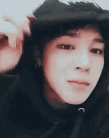 a close up of a person 's face wearing a hoodie and a hat .