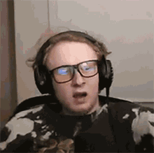 a young man wearing headphones and glasses is making a funny face .
