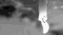 a black and white photo of a candle being lit in a dark room .