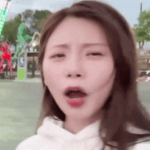a woman is making a funny face in front of a roller coaster .