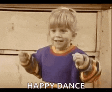 a little boy is dancing and pointing at the camera while wearing a blue shirt .