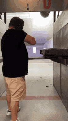 a man is shooting a gun in a shooting range with the letter j on the wall behind him