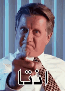 a man in a suit and tie is pointing at the camera with arabic writing on his face