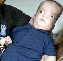 a baby wearing a blue shirt with a dragonfly embroidered on the front