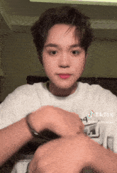 a young man wearing a white shirt has a tiktok sticker on his face