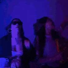 two women are standing next to each other in a dark room with a blue light behind them