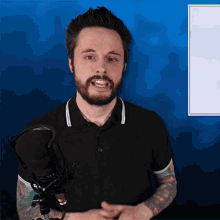 a man with a beard is standing in front of a microphone with a blue background