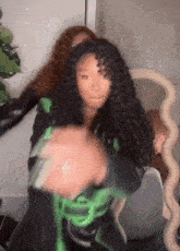a woman with long curly hair is standing in front of a mirror and holding her hair .