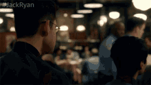 a man wearing glasses stands in a crowded restaurant with the hashtag jackryan