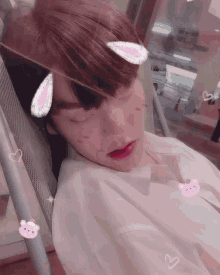 a young man is sleeping in a chair with a cat ear on his head