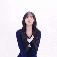 a girl wearing a blue sweater and a blue pleated skirt is giving the peace sign