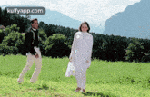 a man and a woman are standing in a grassy field .