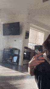 a woman is taking a picture of herself in a living room with a cell phone .