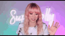 a woman with pink hair is waving her hand in front of a neon sign that says simply