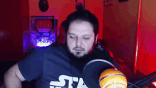 a man with a beard wearing a star wars shirt stands in front of a microphone