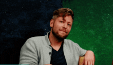 a man with a beard is wearing a gray cardigan