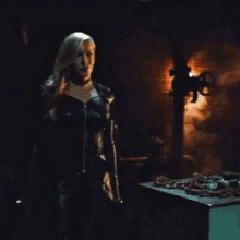 a woman is standing in a dark room holding a sword .