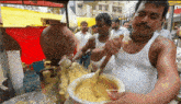 a man in a white tank top is stirring a yellow liquid in a bowl