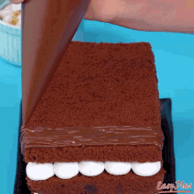 a chocolate cake with marshmallows is being decorated with chocolate frosting