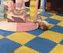 a girl is laying on the floor next to a carousel .