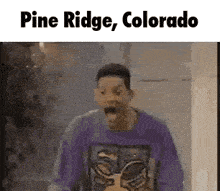 a man in a purple shirt is standing in a room with his mouth open and the words pine ridge colorado on the bottom .
