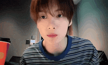 a young man wearing a blue and white striped shirt is looking at the camera