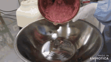 a person pouring something into a metal bowl with the words made in animotica on the bottom
