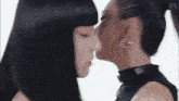 two women with long black hair are kissing each other on the nose
