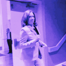 a woman in a suit is walking down a staircase