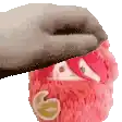 a hand is holding a pink stuffed animal with a crown on it .