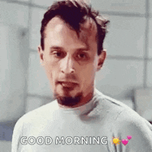 a man with a beard is wearing a gray shirt and saying `` good morning '' .