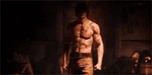 a shirtless man is standing in a dark room .