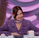 a woman in a purple jacket sits at a table with candles and a book that says aes