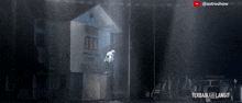 a statue of a man is hanging from a pole in front of a building that says " balai kota " on it